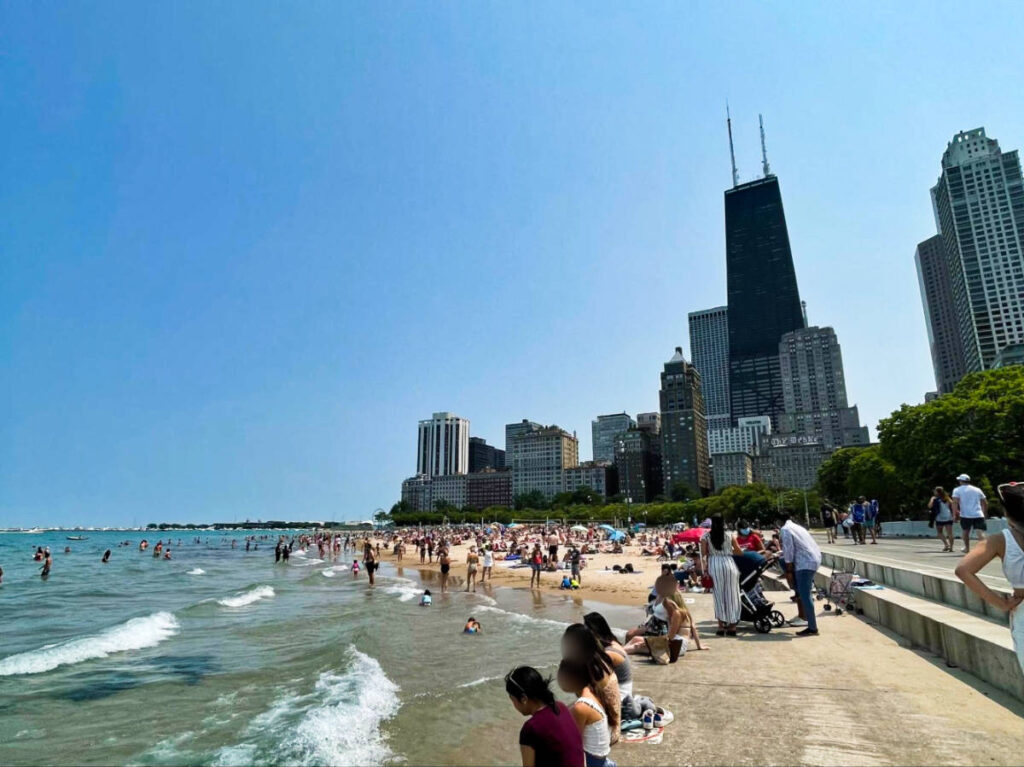 View of the crowd relaxing at the Oak Street Beach with the Chicago skyline in the background