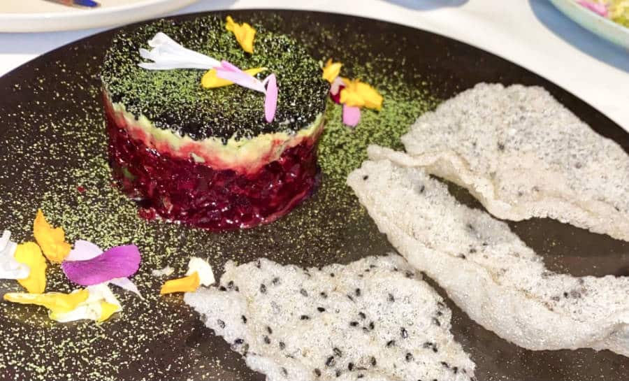 A premium A5 Wagyu tartare with black sesame rice crackers and edible flowers