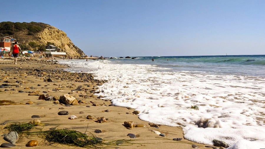 A man walking along the rocky sand of Crystal Cove State Park