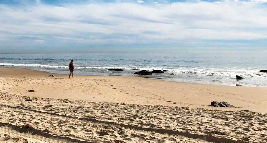 View of a woman walking in the sand of Crystal Cove State Park
