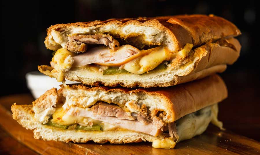 A Cuban sandwich cut in half on a wooden board