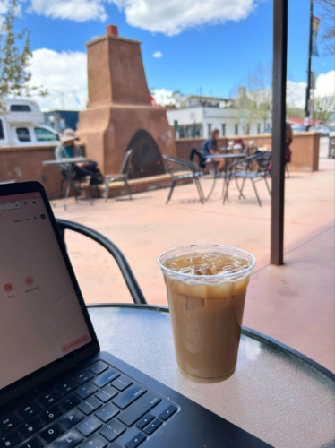 A cup of coffee and laptop on the table at the patio of Buena Vista Roastery Cafe