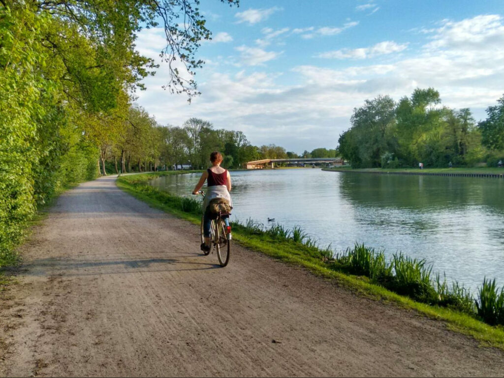 A person cycling along a river path in Münster