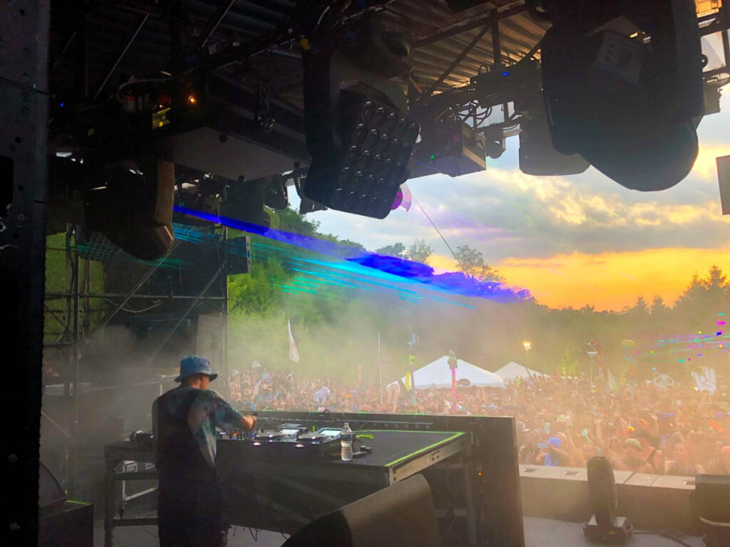 Backstage view of a DJ performing and the crowd enjoying it