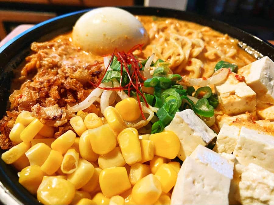 A bowl of spicy creamy ramen with corn, egg and tofu in DTLA Ramen