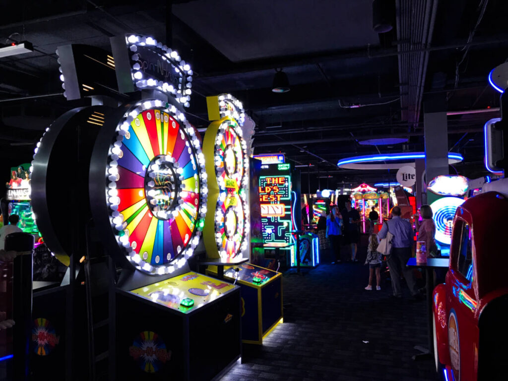 View of the illuminated arcade games and the people inside the dark Dave and Busters