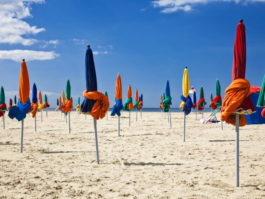View of the closed colorful parasols along the shoreline of Deauville Beach