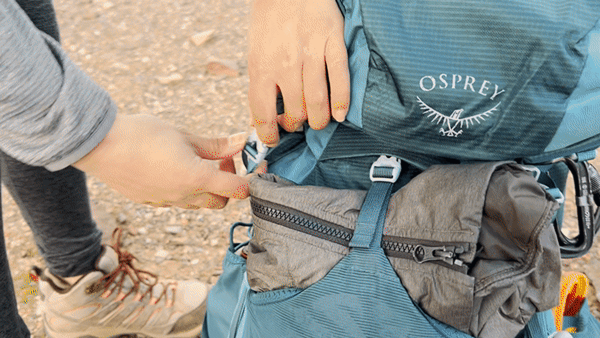 A demonstration of unbuckling the lid of an Osprey Eja Backpack