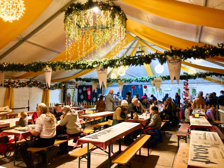 View of people dining at the Denver Christkindl Market with Christmas decorations around