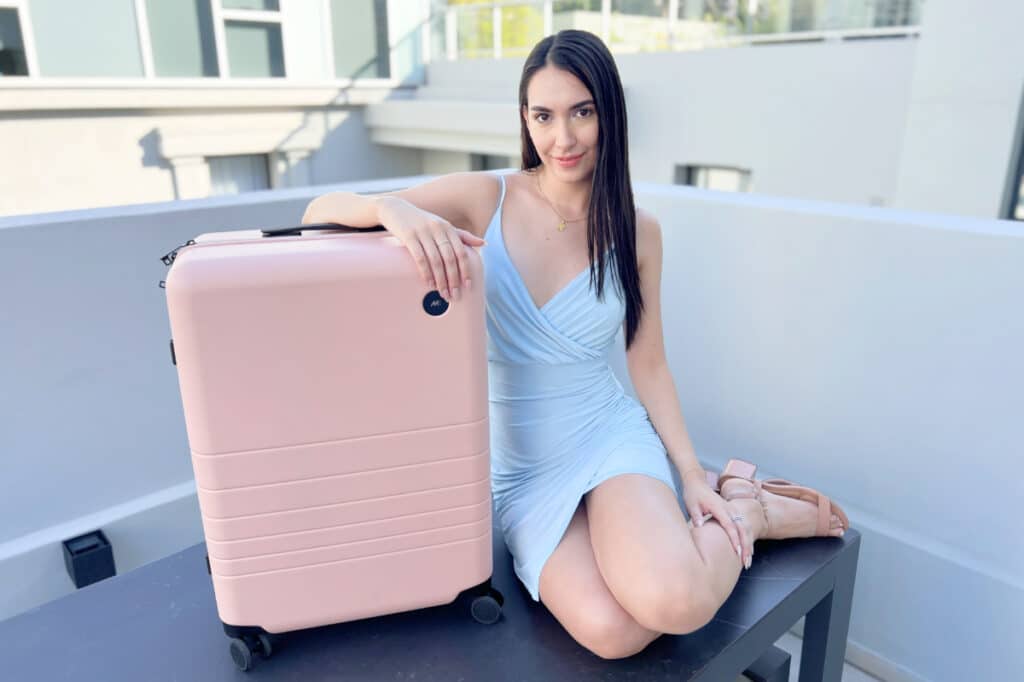 Clara smiling for a photo with the Monos Check-In Medium on her side