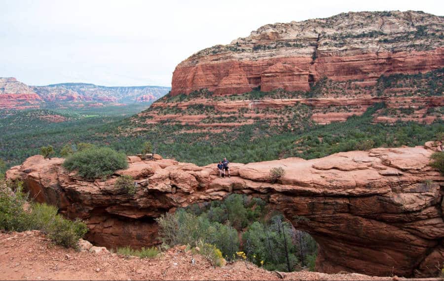 Panoramic view of a couple sitting at the top of Devil’s Bridge in Sedona