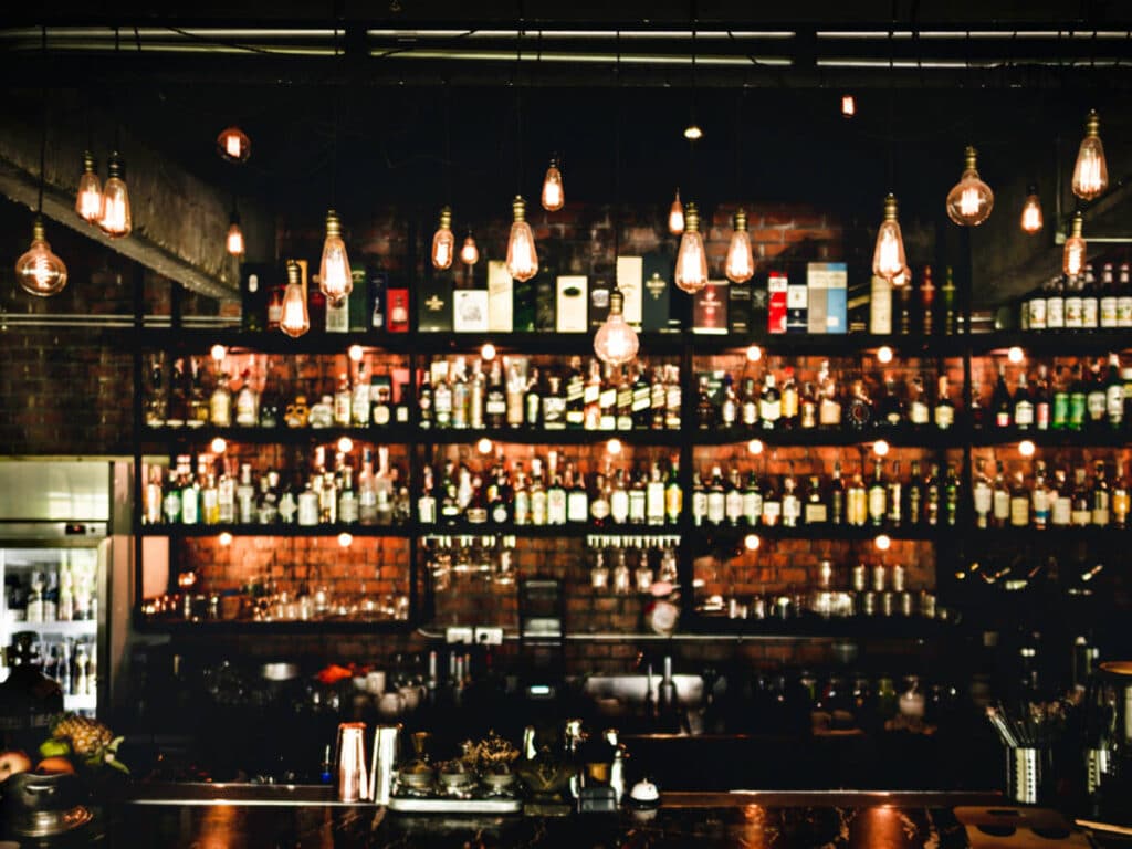 View of the dimly lit bar with displayed alcoholic beverages in the background