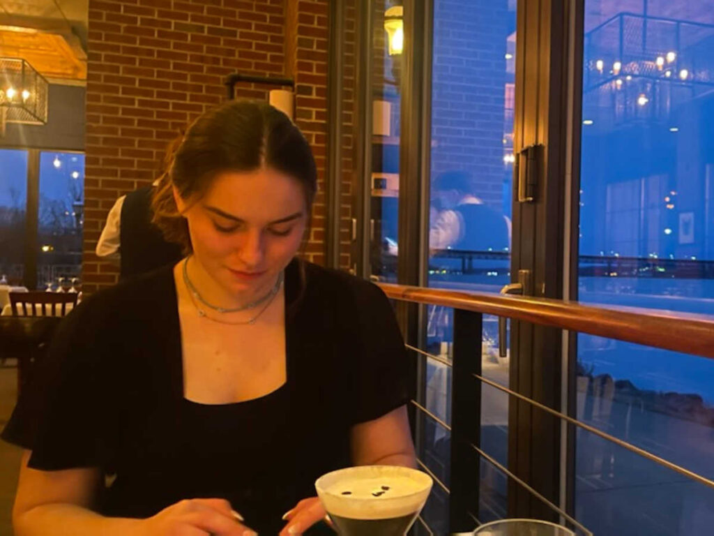 A woman dining with a waterfront view at night