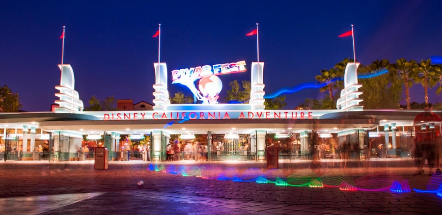 Illuminated Pixar Fest signage above the entrance gate in Disneyland during nighttime
