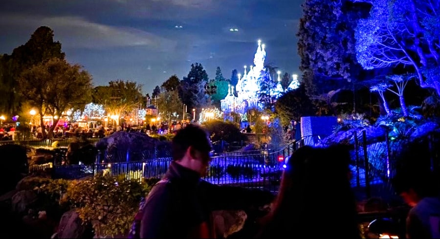 View of the illuminated Disneyland Castle from a distance during nighttime