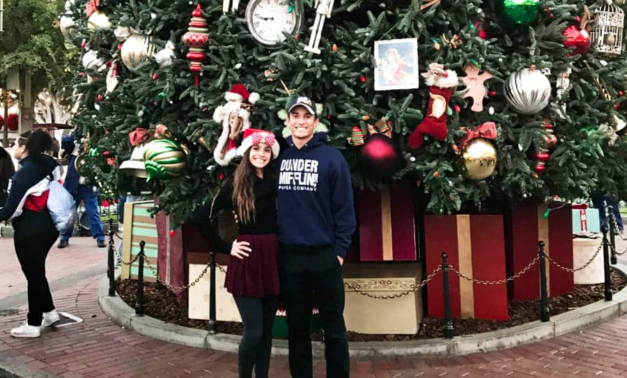The author McKenna Mobley and her brother posing in front of the giant Christmas tree at Disneyland