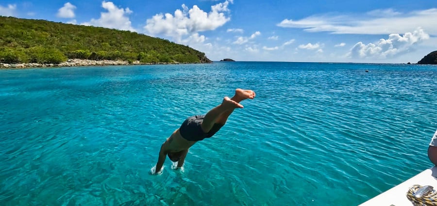 A man diving off the boat to swim to St. John’s shore