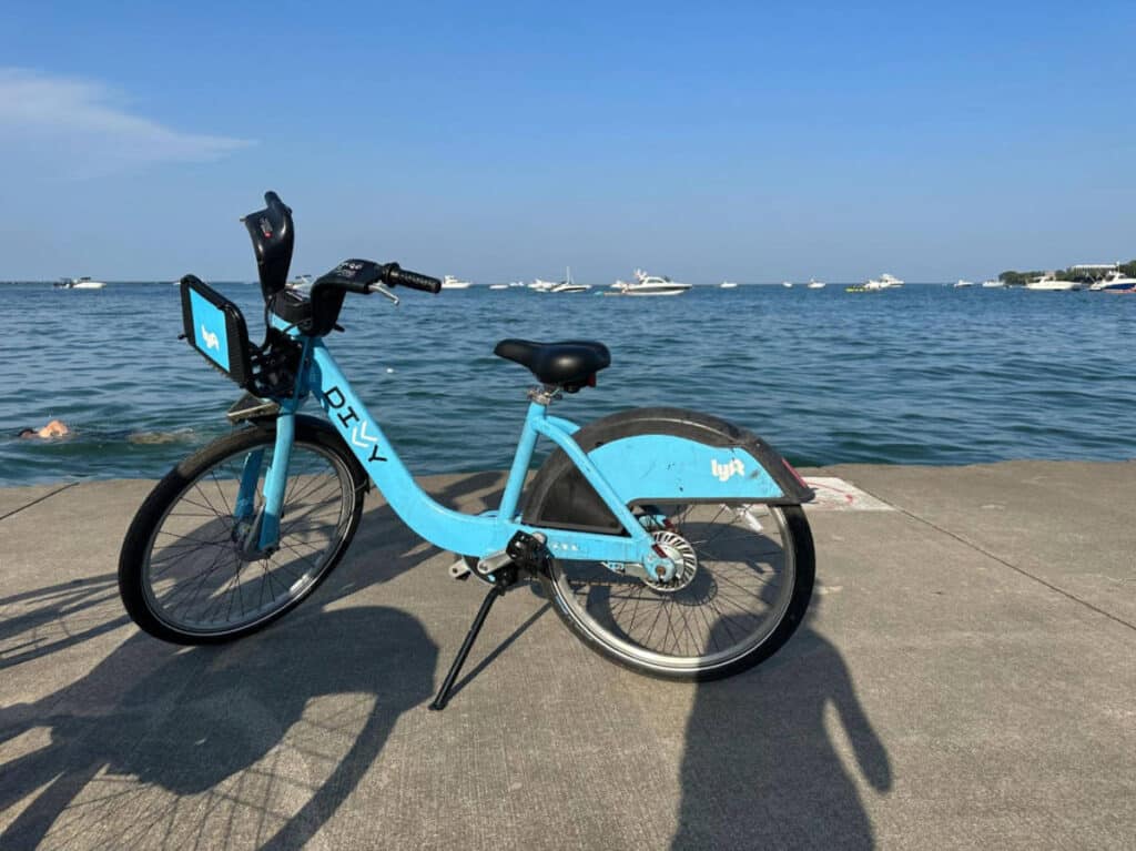A Divvy Bike with boats on the blue water on its background in Chicago