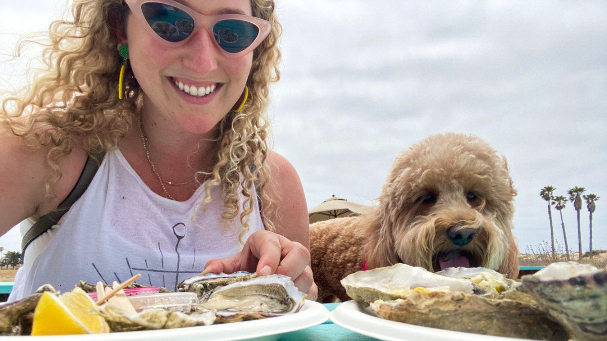 The author Jess Levy with her dog eating oysters at one of the dog-friendly restaurants in San Diego