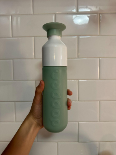 A hand holding a Dopper water bottle