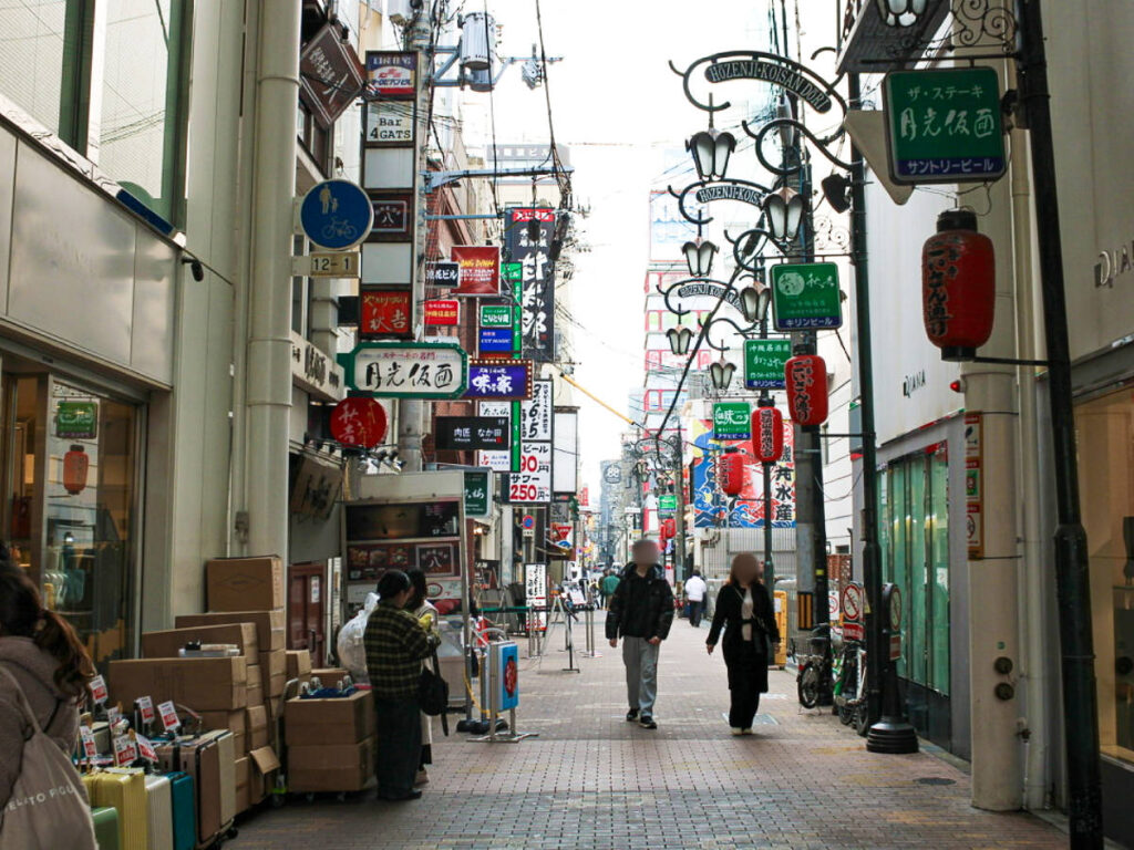 People walking along the alley full of colorful signages in Dotonbori Neighborhood