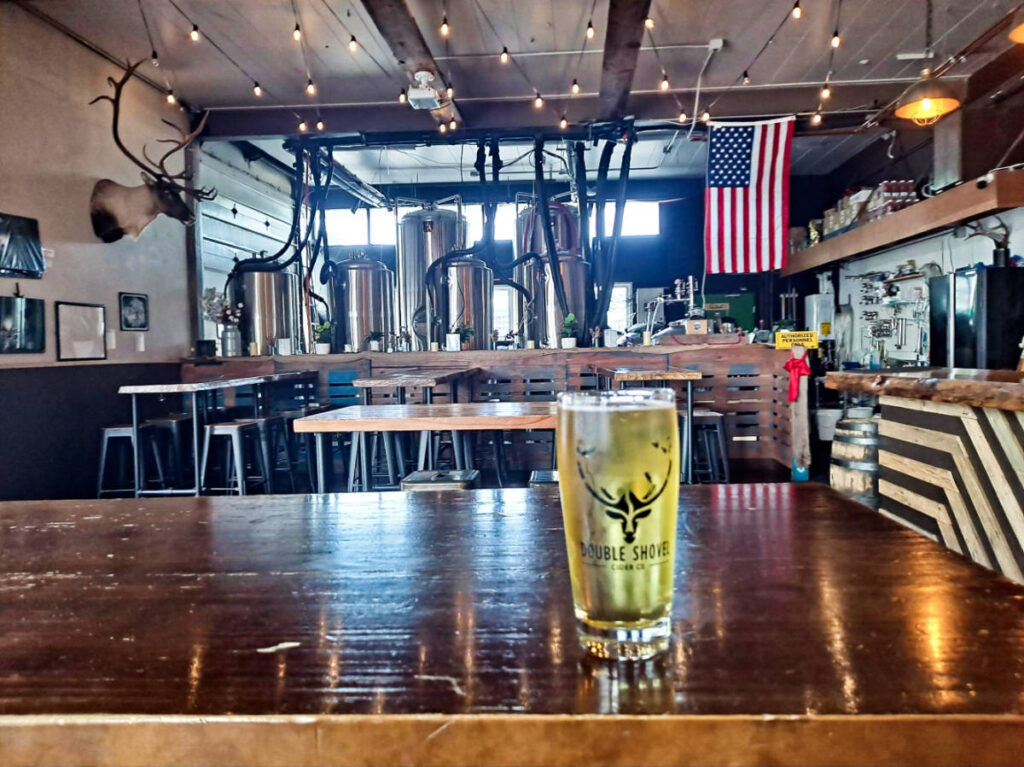 A glass of cider on a wooden table of Double Shovel Cider Kodiak