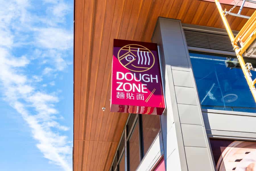 The bright pink signage of Dough Zone outside the restaurant