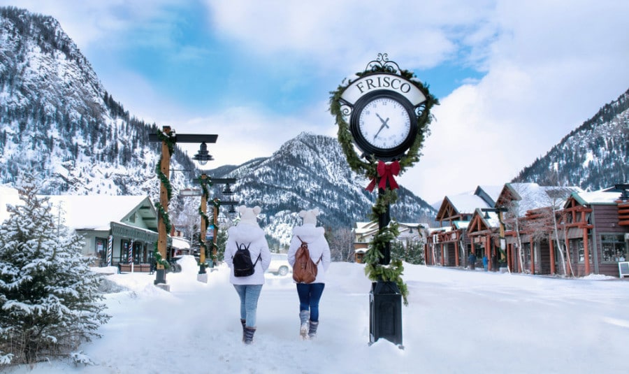 Two girls walking in the mountain with the view of snowcapped mountains and houses in Frisco