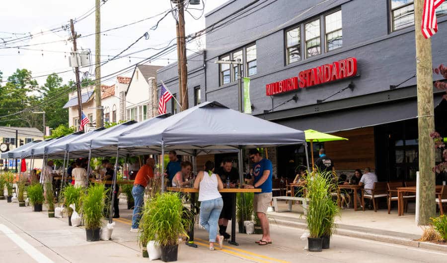 View of people dining outside the table service of restaurants in downtown Millburn
