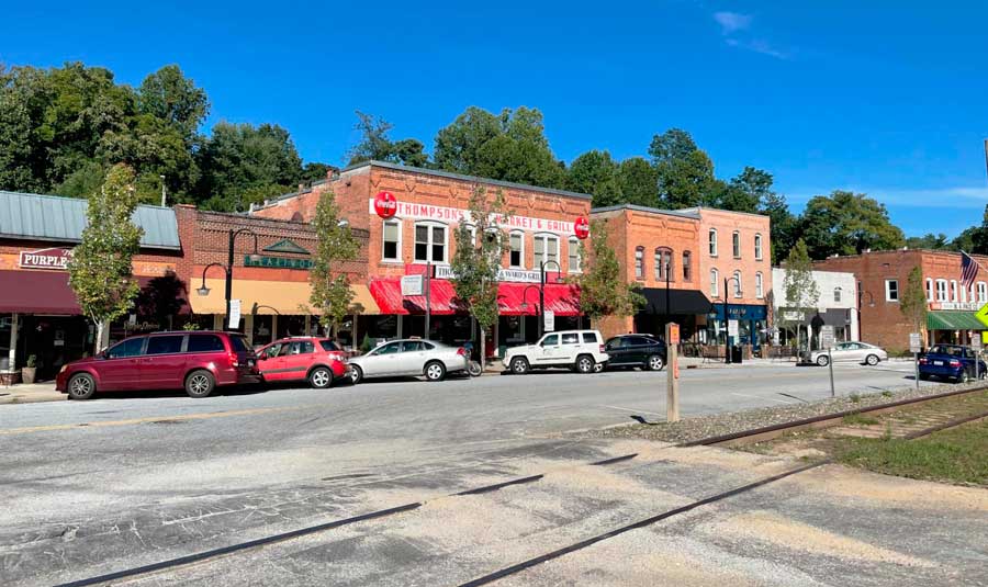 Cars parked on a street in downtown Saluda and a train tracks across it