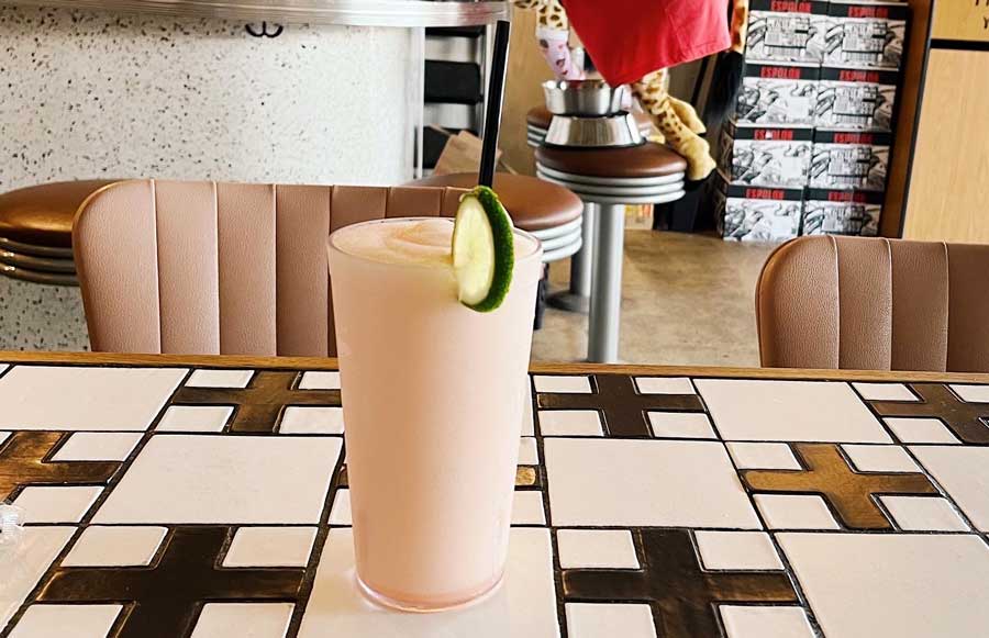 A drink on a glass with lime and straw on it
