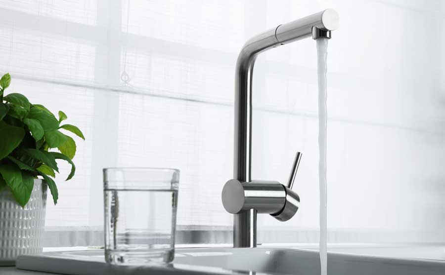 A faucet with water flowing on it and a glass of water next to it