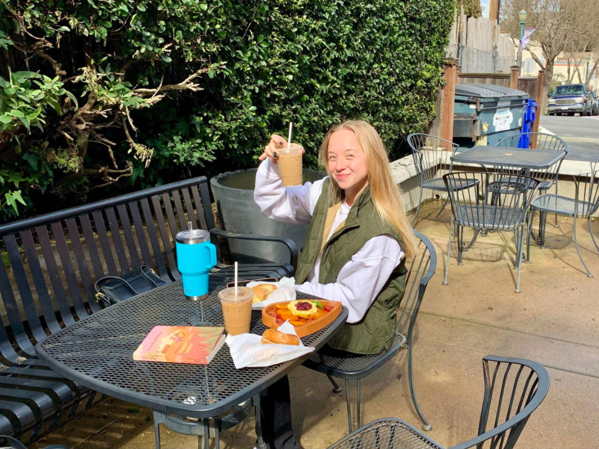 A woman showing her cup of coffee at Madhouse Coffee