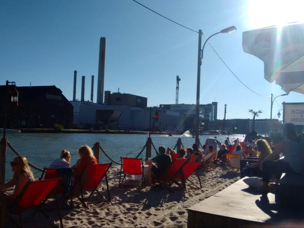 People sitting on chairs near the water, enjoying drinks under the sun in Münster