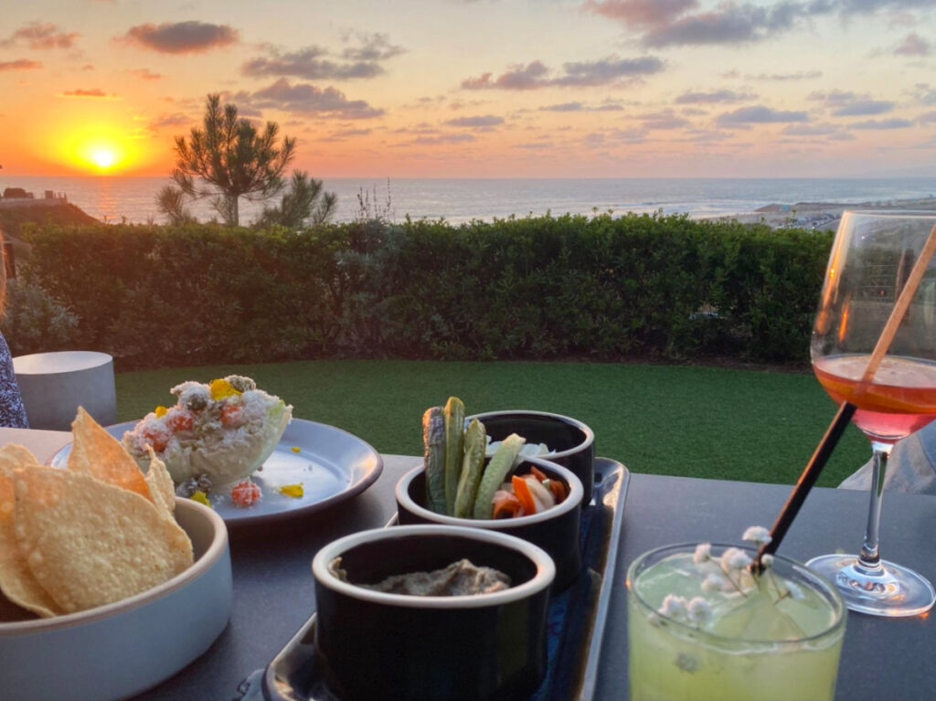 Tapas and wine with sunset in the background at VAGA Restaurant & Bar at Alila Marea Beach Resort