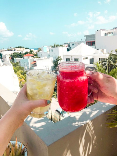 Two people toasting with glasses of drinks on a rooftop