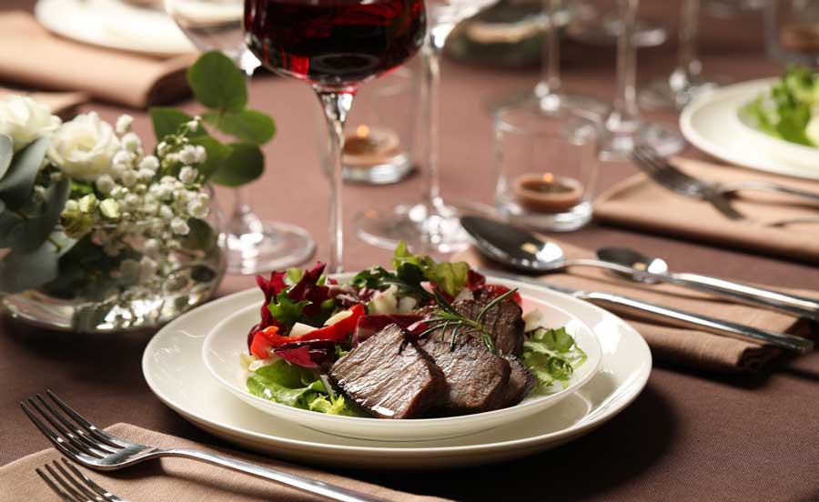 Grilled meat with vegetables on a plate and a glass of red wine