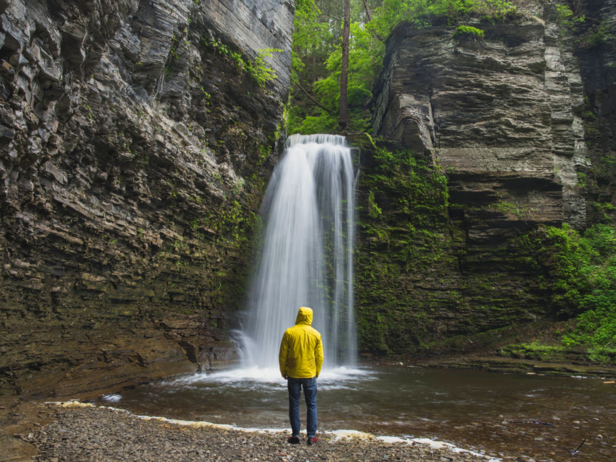 A person wearing a yellow jacket standing in front of Eagle Cliff Falls