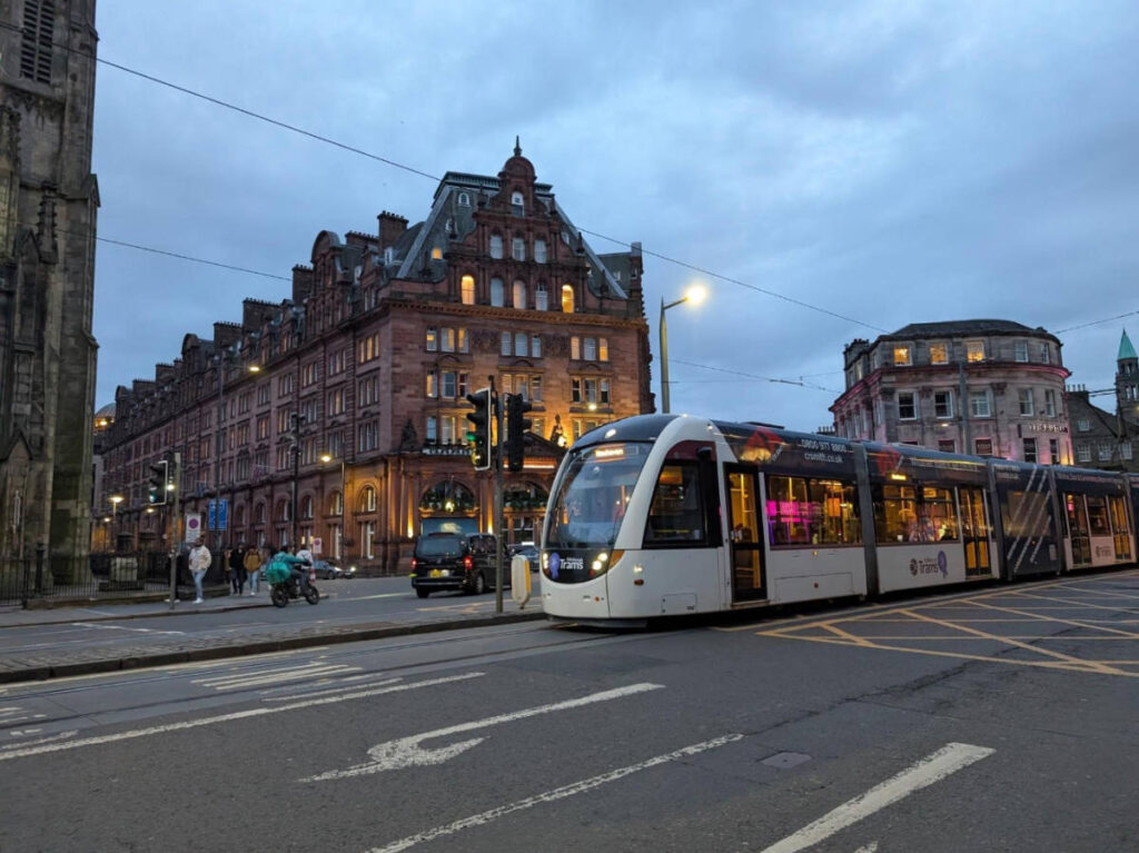 View of an Edinburgh tram passing by a street before night time