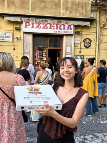 Travel Lemming Editor, Lea Rose, holding a box of pizza outside the L’Antica Pizzeria da Michele