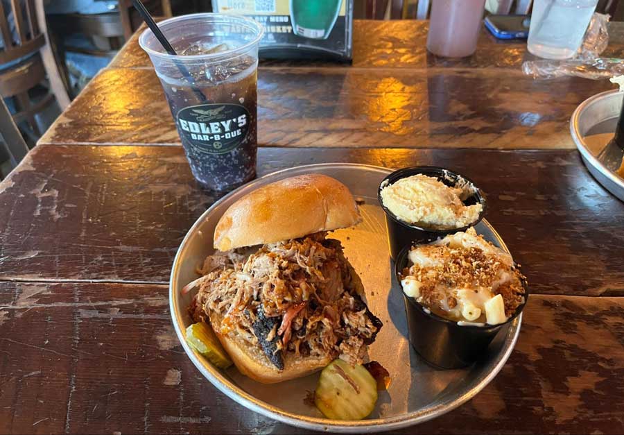 Pork sandwich on a plate and a cup of softdrinks with a straw on a table