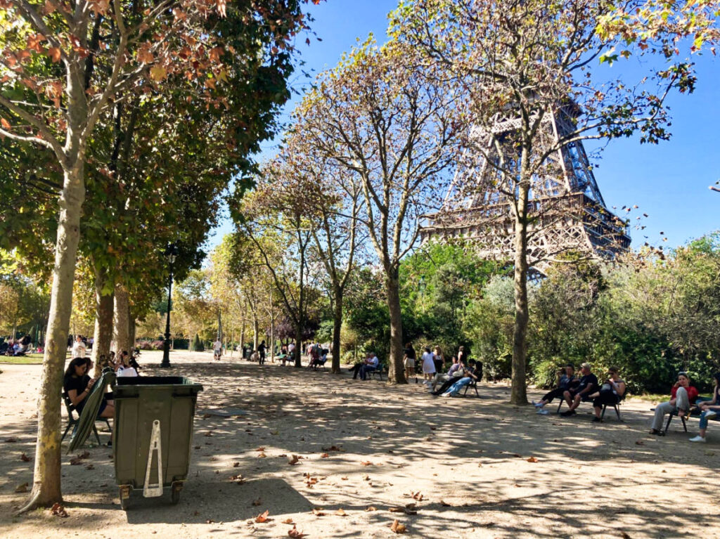 View of the people relaxing on the benches at the park with the Eiffel Tower in the background