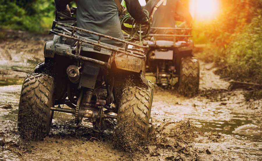 A man riding an ATV on a muddy road