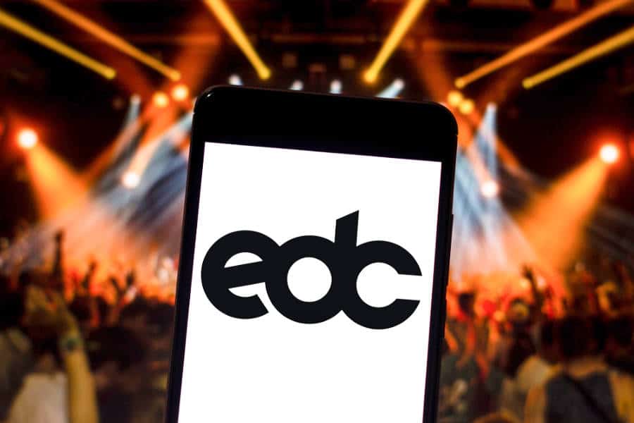 A tablet with edc logo and people partying inside the club in the background