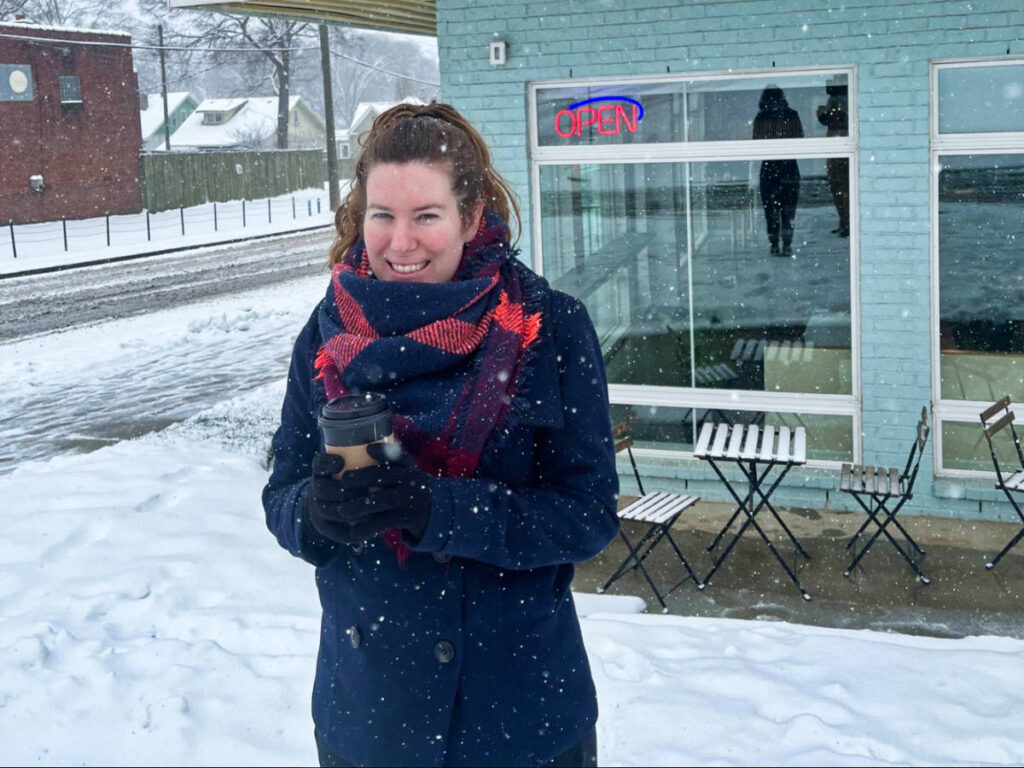 The author Elizabeth Demolat, wearing winter clothes while holding a cup of coffee in Nashville
