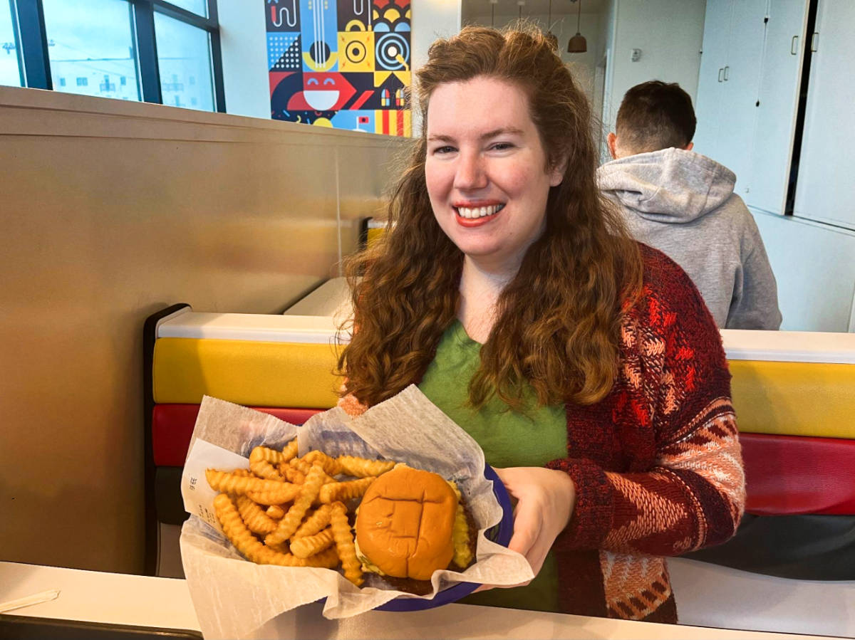 The author Elizabeth Demolat, holding a small basket with hamburger and fries from Joyland