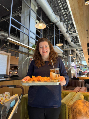 The author Elizabeth holding a food try at the Assembly Food Hall