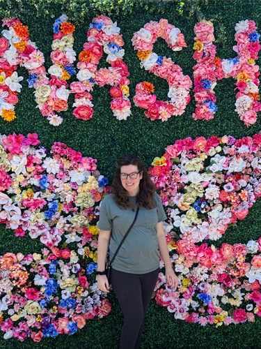 Elizabeth Demolat smiling for a photo with a wings made of flowers on her back