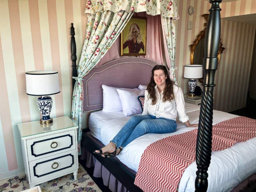 The author Elizabeth Demolat sitting on the bed inside the hotel room in The Graduate Nashville