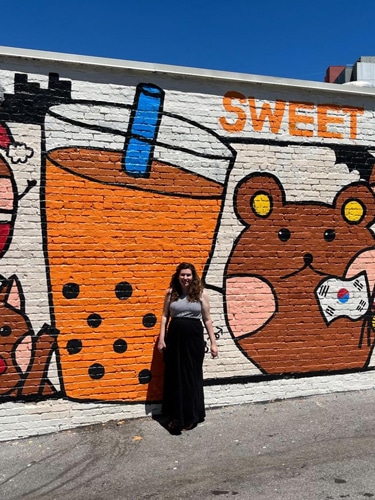 Elizabeth Demolat with a colorful mural on her background